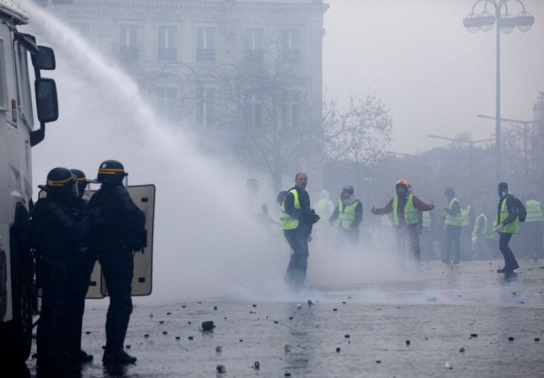 Demonstrators wearing yellow jackets face water cannons near the Champs-Elysees avenue during a demonstration Saturday, Dec.1, 2018 in Paris. French authorities have deployed thousands of police on Paris' Champs-Elysees avenue to try to contain protests by people angry over rising taxes and Emmanuel Macron's presidency.