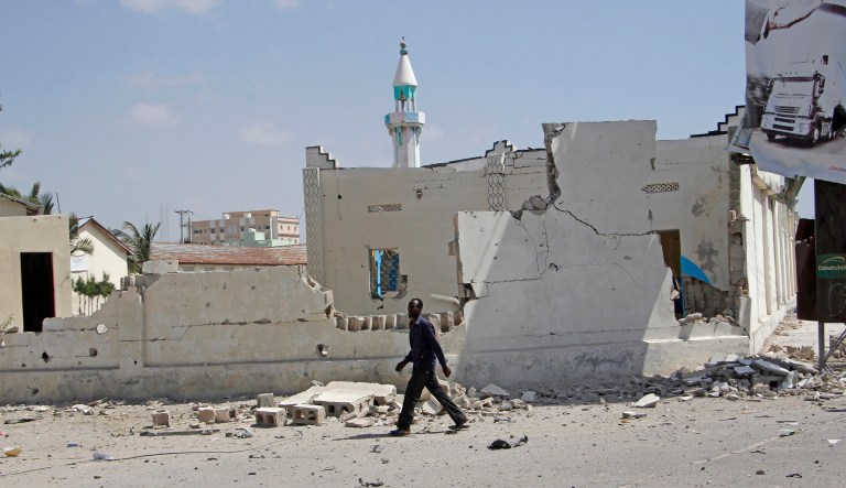 A man walks past destroyed buildings after a large blast in the capital city of Mogadishu, Somalia, Saturday, Dec. 22, 2018. Police say a suicide car bomb exploded near the presidential palace killing and injuring a number of people.
