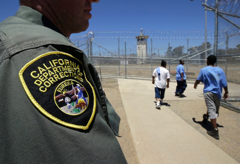 Inmates pass a correctional officer as they leave an exercise yard in Vacaville, Calif. 