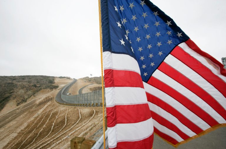 In this July 6, 2009 file photo, an American flag flies during a ceremony held in front of the completed Smuggler's Gulch project along the U.S.-Mexico border in San Diego. 