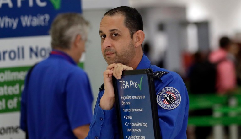 A Transportation Security Administration (TSA) employee works at a security checkpoint at Miami International Airport, Friday, Jan. 18, 2019, in Miami. The three-day holiday weekend is likely to bring bigger airport crowds.