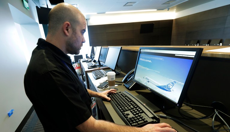 Terry Brown, of Alaska Airlines, makes adjustments on a computer terminal at a gate in the new passenger terminal at Paine Field, Wednesday, Jan. 23, 2019, in Everett, Wash. Alaska Airlines says it will delay the start of commercial passenger service at the new terminal by at least three weeks due to the ongoing partial shutdown of the federal government, as the officials who must sign off on a final environmental assessment are on furlough.