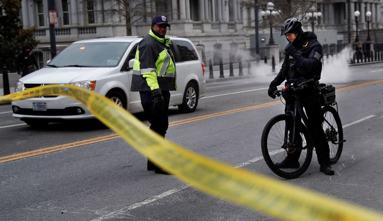 With steam from an underground grate in the background, a Metropolitan Police officer and Secret Service Police officer react to a large gust of frigid wind while blocking the road on 17th Street at the intersection with Pennsylvania Avenue near the White House in Washington, Wednesday, Jan. 30, 2019. 