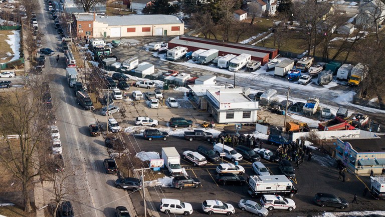 Law enforcement personnel gather near the scene of a shooting at an industrial park in Aurora, Ill.