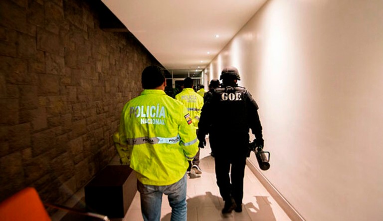 This Friday, April 12, 2019 handout photo provided by the State Attorney General's Office, shows police entering the apartment building where Swedish programmer Ola Bini was residing in Quito, Ecuador. The 36-year-old Swedish programmer was arrested Thursday in an alleged plot to blackmail the countryâs president over his abandonment of Julian Assange.