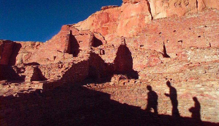 FILE - In this Nov. 21, 1996, file photo, tourists cast their shadows on the ancient Anasazi ruins of Chaco Canyon National Historic Park in New Mexico. Advocates for greater restrictions on oil and natural gas drilling near ancient Native American cultural sites in the Southwest are urging Congress to establish new precautions. A congressional subcommittee on energy ventured thousands of miles from Washington to hold a field hearing Monday, April 15, 2019 on the impacts of air pollution on sacred ruins and landmarks. New Mexico's delegation to Washington wants to halt new drilling leases near Chaco Culture National Historic Park.