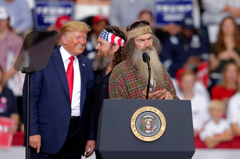 President Donald laughs with Willie Robertson, of the reality TV series Duck Dynasty, and Phil Roberston, the family patriarch, right, at a campaign rally in Monroe, La. Nov. 6, 2019.
