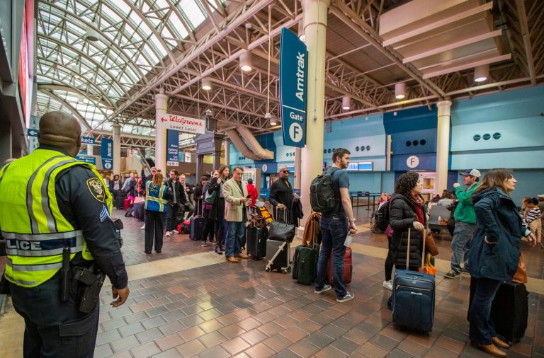 Amtrak Police officer stands guard with travelers waiting in line at Union Station in Washington, Wednesday, Nov. 27, 2019.