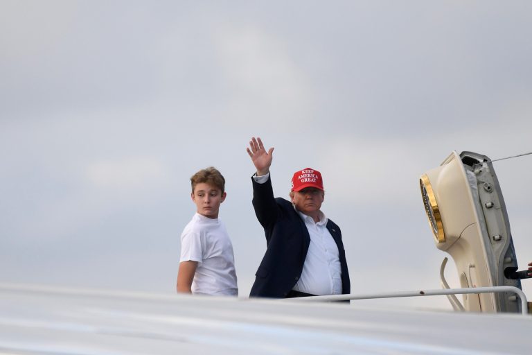 President Donald Trump, standing with his son Barron, waves from the top of the steps of Air Force One at Palm Beach International Airport in West Palm Beach, Fla., Sunday, Dec. 1, 2019. 