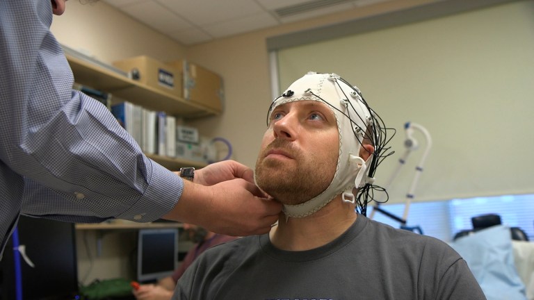 In this Nov. 20, 2019, image from video, Zach Ault is fitted with an EEG cap which uses electrodes to track the electrical activity of his brain, at the National Institutes of Health's hospital in Bethesda, Maryland. Ault has ME/CFS, what once was called 