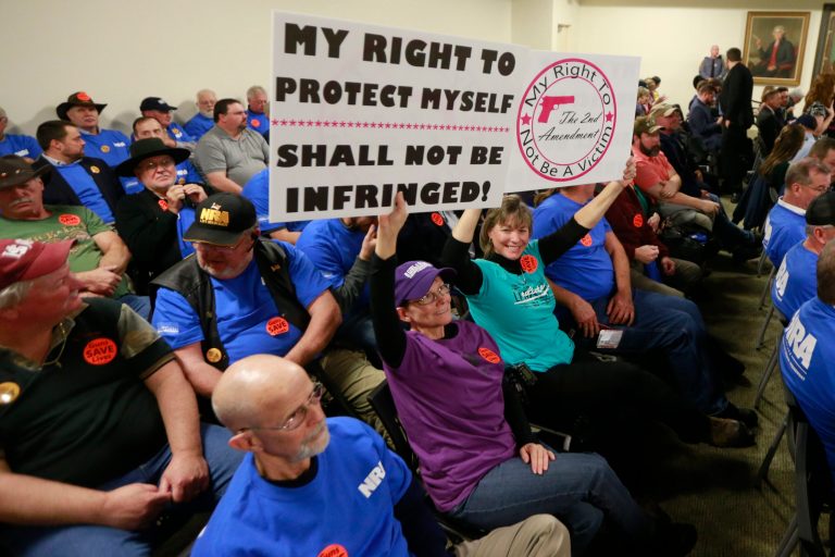Gun rights protesters hold signs prior to the start of a meeting of the Senate Judiciary committee at the Capitol in Richmond, Va., Monday, Jan. 13, 2020. The Committee passed several bills related to gun laws.