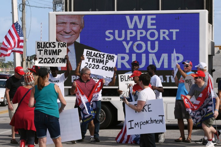 Supporters, some holding "Blacks for Trump" signs, gather along Southern Boulevard as President Donald Trump's motorcade returns to Mar-a-Lago from the Trump International Golf Club located in West Palm Beach, Saturday, Jan. 18, 2020.