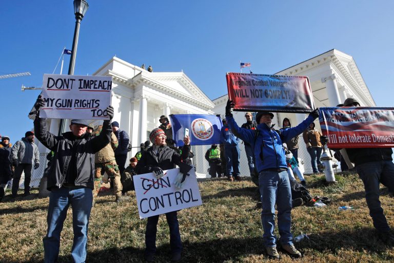 Pro-gun demonstrators hold a flag and signs in front of the Virginia State Capitol Monday, Jan. 20, 2020, in Richmond, Va. The battle over guns has split the state.