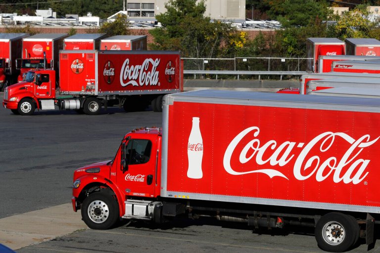 FILE - In this Oct. 14, 2019 photo a truck with the Coca-Cola logo, behind left, maneuvers in a parking lot at a bottling plant in Needham, Mass. The Coca-Cola Co. reports financial results on Thursday, Jan. 30, 2020. 