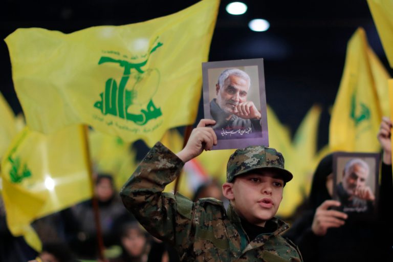 A Hezbollah supporter holds pictures of slain Iranian Revolutionary Guard Gen. Qassem Soleimani during a ceremony marking the anniversary of the assassination of Hezbollah leaders, Abbas al-Moussawi, Ragheb Harb and Imad Mughniyeh and the end of a 40-day Muslim mourning period for Soleimani, in the southern suburb of Beirut, Lebanon, Sunday, Feb. 16, 2020.