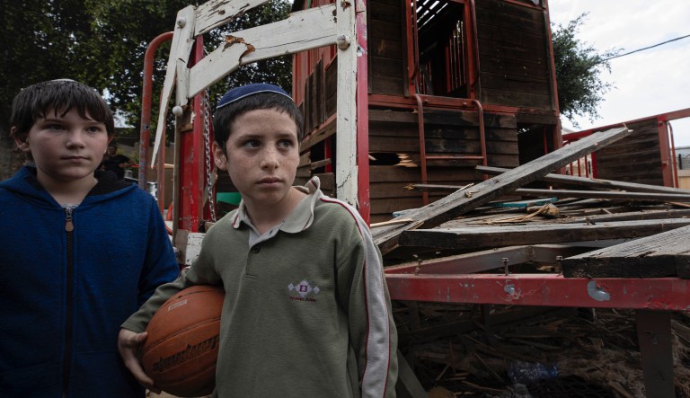 Boys stand inside a kindergarten's playground that was hit by a missile fired from Gaza Strip in the city of Sderot, Israel, Monday, Feb. 24, 2020. Gaza militants resumed their intense bombardment of southern Israel on Monday, with some rockets slipping through Israel's Iron Dome defense system and one landing in the yard of a kindergarten.