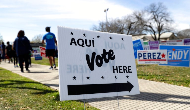 In this photo, pedestrians pass signs near a polling site in San Antonio.