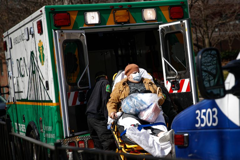 A patient wears a protective face mask as she is loaded into an ambulance at The Brooklyn Hospital Center emergency room, Wednesday.