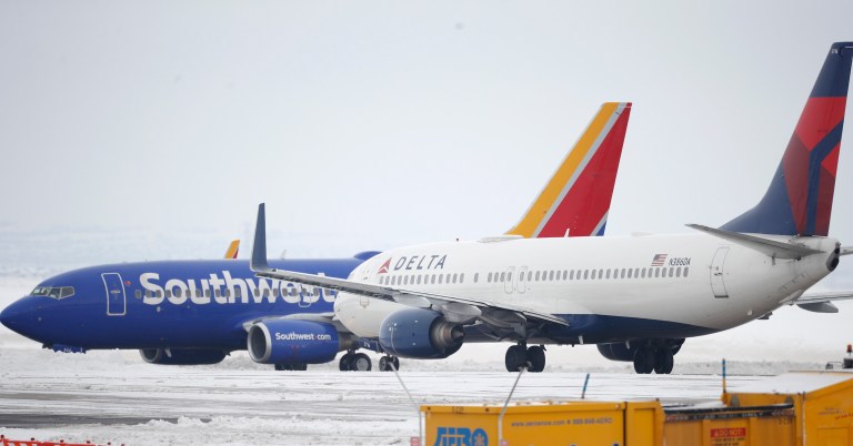 A Delta Airlines jetliner waits for a Southwest jetliner to taxi pst on the way to a runway for take off from Denver International Airport. 
