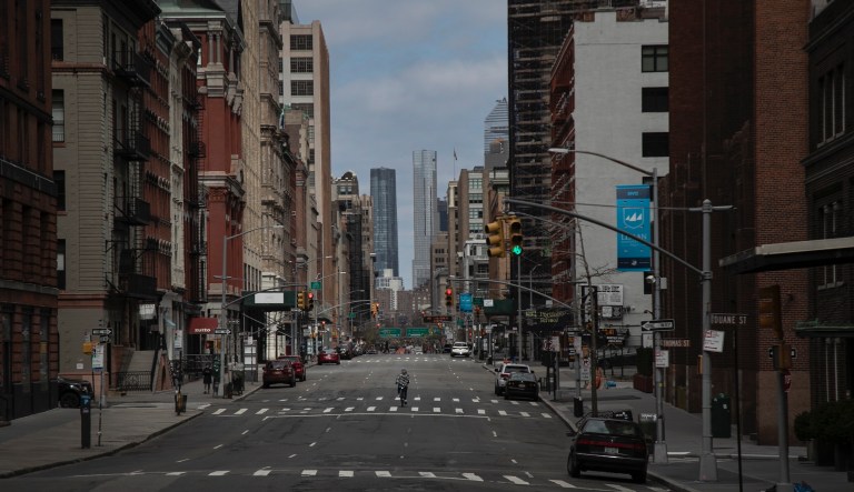 A cyclist rides his bicycle down the middle of a main road in downtown New York, on Sunday, March 22, 2020.