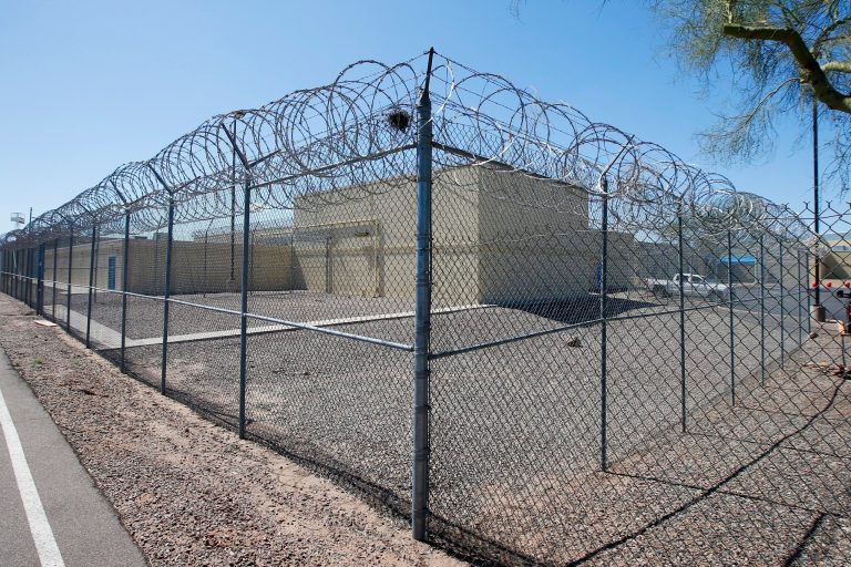 This file photo shows barbed wire fences at the Maricopa County Estrella Jail in Phoenix in March. At jails across Arizona, visitation has been suspended, jail workers are checking to see if people being booked are showing symptoms of COVID-19. The National Sheriffs' Association and the REFORM Alliance have teamed to deliver PPE to national jails.