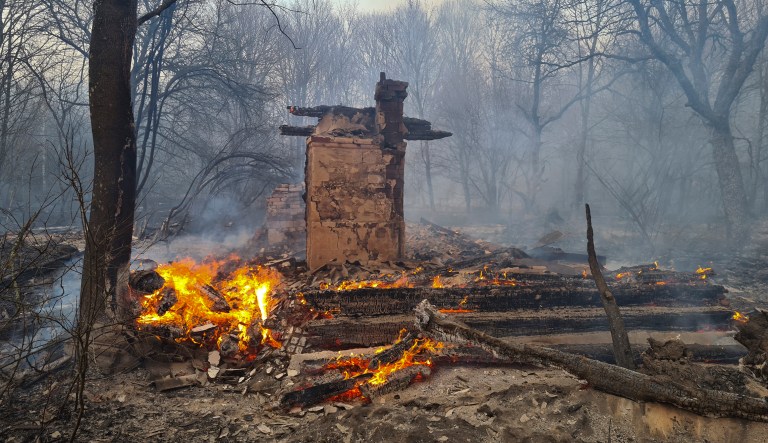 An uninhabited house burns in the middle of a forest fire near the village of Volodymyrivka, in the exclusion zone around the Chernobyl nuclear power plant in Ukraine, on April 5, 2020. Ukrainian firefighters are laboring to put out two forest blazes in the area around the Chernobyl nuclear power station that was evacuated because of radioactive contamination after the 1986 explosion at the plant.  