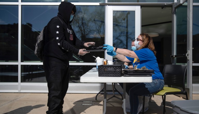 In this Wednesday, April 8, 2020 photo, tenth-grader Yusiel Tlacoxochitecatl receives a computer from Principal Christine Borelli at Benjamin Franklin High School in Philadelphia. Pennsylvania schools will remain shuttered for the rest of the academic year because of the coronavirus pandemic that has sickened thousands and caused hundreds of deaths statewide, under an order signed Thursday by the state education secretary.