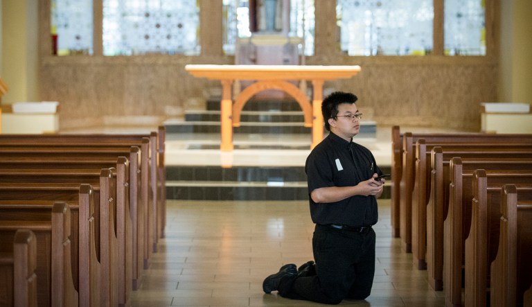 The Rev. Vincent Tran, parochial vicar, kneels as he participates in the Good Friday praying of the Stations of the Cross, Friday, April 10, 2020, at Christ the Redeemer Catholic Church in Houston.