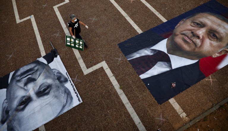 A woman takes part in a protest against Israeli Prime Minister Benjamin Netanyahu, seen on the poster left while Turkish President Recep Tayyip Erdogan is on the other poster, in Tel Aviv, Israel, Sunday, April 19, 2020.