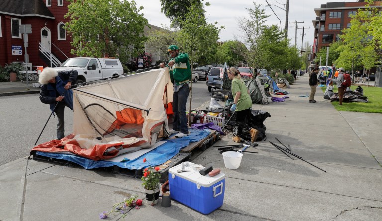 A group of people dismantle a tent at a homeless encampment being cleared Monday, May 4, 2020, at Ballard Commons Park in Seattle. (AP Photo/Ted S. Warren)