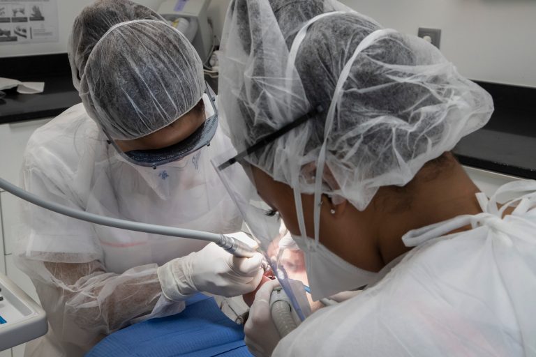 In this Wednesday, May 13, 2020 photo, dentist Sabrine Jendoubi, left, and her dental assistant Margot Daussat inspect the teeth of patient Veronique Guillot, during a dental appointment  at a dental office in Paris. (AP Photo/Michel Euler)