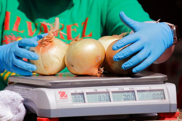 In this Sunday, May 3, 2020 file photo, a farmer weighs onions for a customer at a farmers market during its first opening in nearly two months because of the coronavirus outbreak in Seattle.