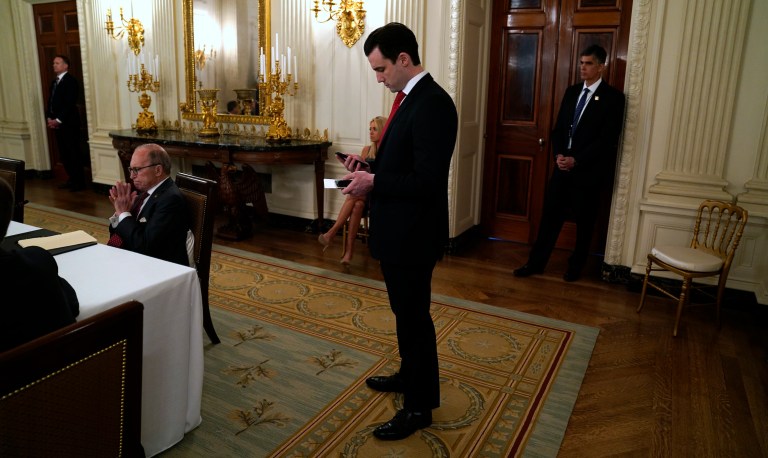 White House special assistant to the president Nick Luna checks his phone as President Donald Trump speaks during a meeting in the State Dining Room of the White House, Monday, May 18, 2020