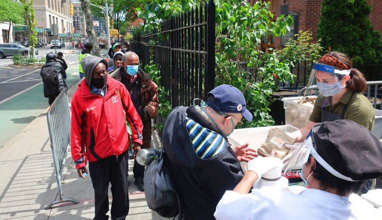 Ginger Pierce, center, and Pablo Guzman, right, hand out food at the Holy Apostle Soup Kitchen in New York City during the coronavirus pandemic on Tuesday, May 19, 2020.