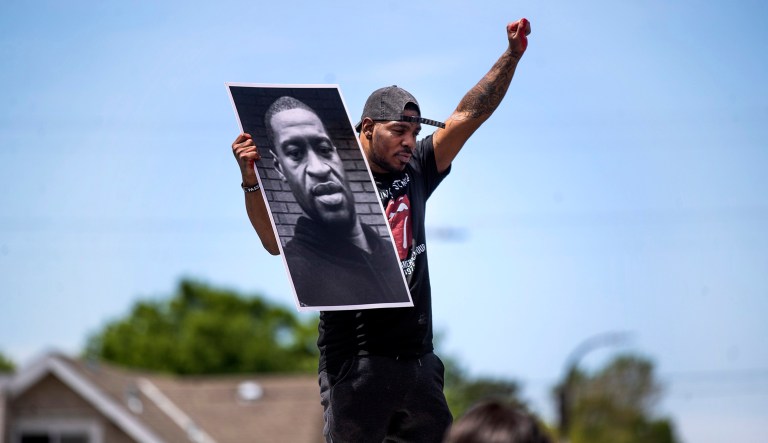 Tony L. Clark holds a photo of George Floyd outside the Cup Food convenience store on May 28, 2020, in Minneapolis. Floyd, a handcuffed black man, died in police custody near the convenience store. 