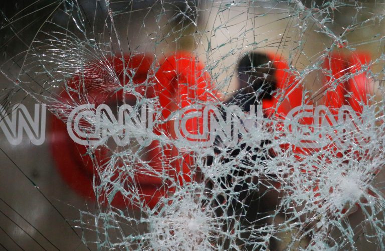 A security guard walks behind shattered glass at the CNN building at the CNN Center in the aftermath of a demonstration against police violence on Saturday, May 30, 2020, in Atlanta. A CNN guest on Sunday held CNN up as journalism's model.