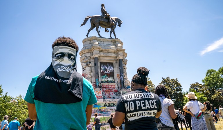 People gather at the Robert E. Lee Monument, now covered by protest graffiti, in Richmond, Va., Sunday, June 7, 2020, following a week of unrest in the U.S. against police brutality and racism in policing. The statue of the Confederate Civil War general is slated for removal at the order of Gov. Ralph Northam.