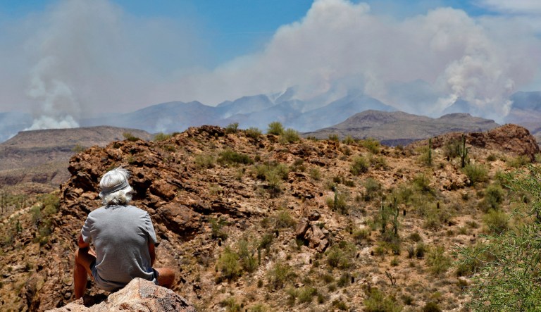 Steve Boesman, of South Dakota, watches a portion of the Bush fire burn through the Tonto National Forest, Tuesday, June 16, 2020, as seen from Apache Junction, Ariz. The wildfire, which has prompted evacuations in three rural communities and closed parts of two state highways, has grown dramatically in size from 59 square miles to 101 square miles as of Tuesday morning officials said.