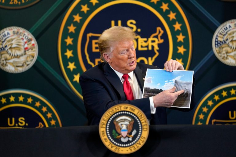 President Donald Trump holds an image of the U.S. border wall being built between the U.S. and Mexico as he participates in a border security briefing at United States Border Patrol Yuma Station, Tuesday, June 23, 2020, in Yuma, Ariz.