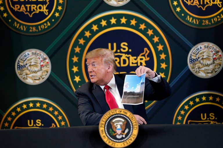 President Donald Trump holds an image of the U.S. border wall being built between the U.S. and Mexico as he participates in a border security briefing at United States Border Patrol Yuma Station, Tuesday, June 23, 2020, in Yuma, Ariz.
