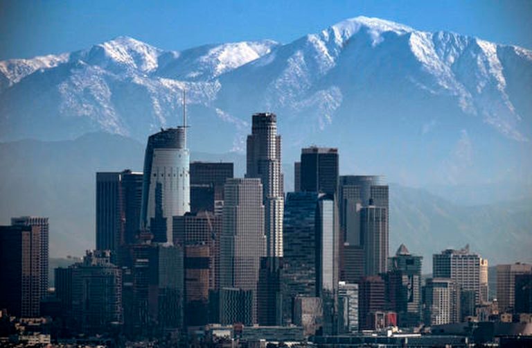 FILE - In this Jan. 25, 2017, file photo, a snow-covered Mount Baldy, the highest peak among the San Gabriel Mountains, looms behind downtown Los Angeles. (AP Photo/Richard Vogel, File)