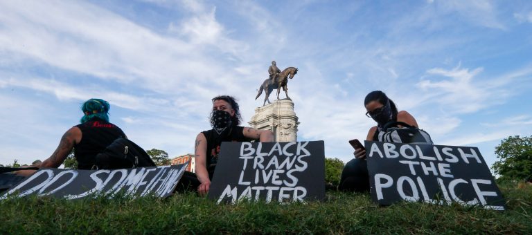 In June, protesters hold signs near the statue of Confederate General Robert E. Lee on Monument Avenue in Richmond, Va. The city is bracing for another protest tonight.