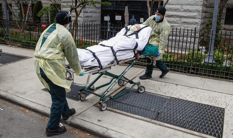 In this April 17, 2020, file photo, a patient is prepared to be loaded into the back of an ambulance by emergency medical workers outside Cobble Hill Health Center in the Brooklyn borough of New York. 