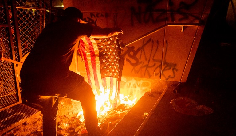 A Black Lives Matter protester burns an American flag outside the Mark O. Hatfield United States Courthouse on Monday, July 20, 2020, in Portland, Ore.
