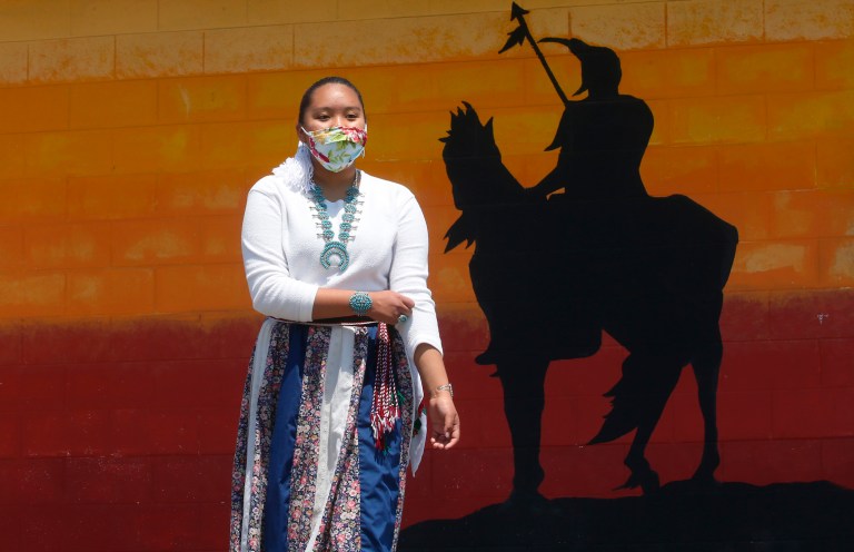 Lemiley Lane, a Bountiful junior who grew up in the Navajo Nation in Arizona, walks along the campus near a a mural of an Indigenous man meant to represent the Braves mascot at Bountiful High School, July 21, 2020, in Bountiful, Utah. While advocates have made strides in getting Native American symbols and names changed in sports, they say there's still work to do mainly at the high school level, where mascots like Braves, Indians, Warriors, Chiefs and Redskins persist. 