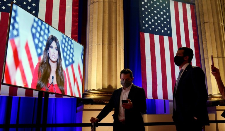 Donald Trump Jr., right, watches as his girlfriend Kimberly Guilfoyle, tapes her speech for the first night of the Republican National Convention from the Andrew W. Mellon Auditorium in Washington