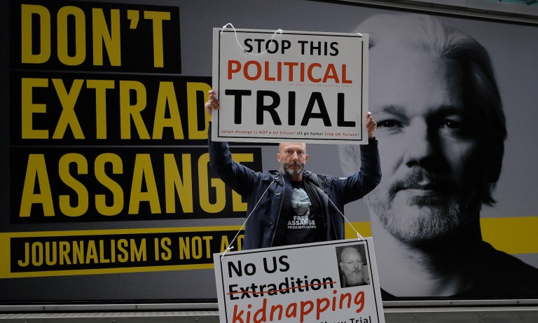 A demonstrator holds placards near the Central Criminal Court Old Bailey in London, Tuesday, Sept. 8, 2020. Lawyers for WikiLeaks founder Julian Assange and the U.S. government were squaring off in a London court on Monday at a high-stakes extradition case delayed by the coronavirus pandemic. American prosecutors have indicted the 49-year-old Australian on 18 espionage and computer misuse charges over Wikileaks' publication of secret U.S. military documents a decade ago. The charges carry a maximum sentence of 175 years in prison. 