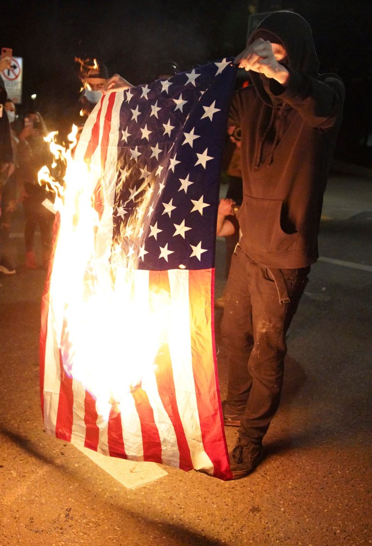 A protester burns an American flag while rallying at the Mark O. Hatfield United States Courthouse on Saturday, Sept. 26, 2020, in Portland, Ore. A new Heritage Foundation ad campaign warns of more riots if the left wins the election.