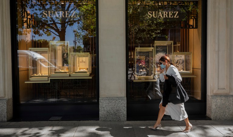 A woman walks past a jewelry store in the upmarket neighborhood of Salamanca in Madrid, Spain, Monday, Sept. 28, 2020. The extended region around Madrid, comprising a population of 6.6 million, is struggling to control coronavirus outbreaks. Heightened restrictions in some of Madrid's working-class neighborhoods brought a heated debate over the prevalence of inequality in Spain. 