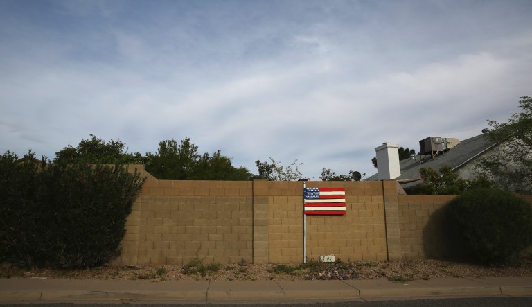 A makeshift U.S. flag stands behind a home located near the intersection between the Arizona State Route 101 and the Interstate 17 freeway in Phoenix, Ariz., on March 9, 2020.